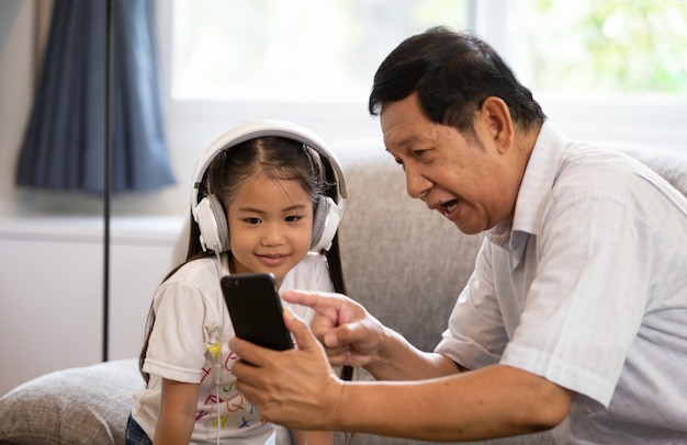 anziani o nonno e bambini che ascoltano musica e giocano insieme nel soggiorno