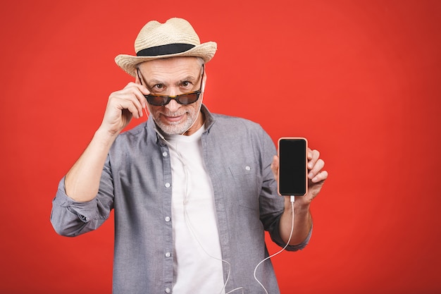 Anziano invecchiato allegro che ascolta la musica su un telefono isolato.