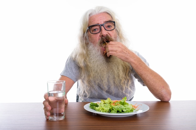 anziano uomo barbuto che indossa occhiali da vista mentre mangia