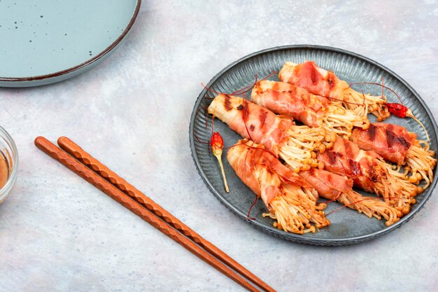 Aperitivo a base di funghi Enoki fritti nel bacon Bacon e rotolo di funghi Enoki cucina asiatica