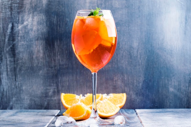 Aperitivo cocktail estivo con ghiaccio di frutta amara all'arancia e soda in vetro alto sfondo grigio argento fuoco selettivo