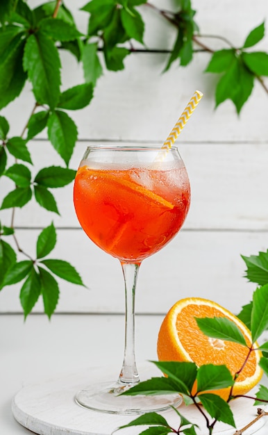 Aperol spritz cocktail con arancia su superficie di legno bianco.