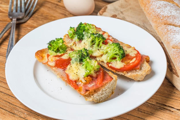 Aperto panino con prosciutto, mozzarella e pomodori sul tavolo da cucina, fuoco poco profondo