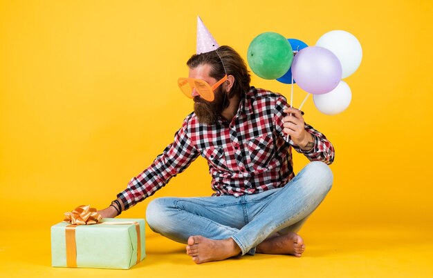 Aperto regalo hipster sorridente felicemente divertendosi sulla festa prepararsi per le vacanze Event Manager pone con accessorio festivo divertimento e concetto di felicità uomo felice che tiene palloncini colorati di elio