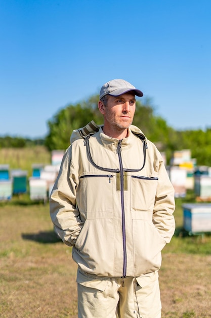 Apicoltore di miele estivo Uomo in tuta protettiva per apicoltura in apiario