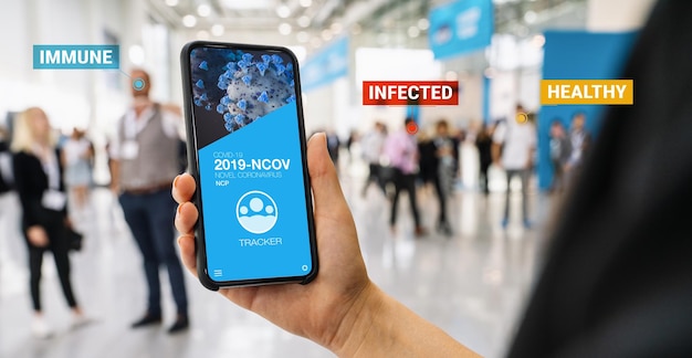 app di monitoraggio del coronavirus su uno smartphone mobile. Primo piano di una donna che segue la folla di persone in un'applicazione per lo schermo dello smartphone. Dispositivo intelligente per la tenuta della mano. Sito Web di simulazione. tracker del virus corona covid-19