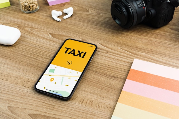 App Taxi Service sullo schermo dello smartphone sul tavolo di legno. Ambiente d'ufficio. Fornitore di servizi di mobilità in tutto il mondo.