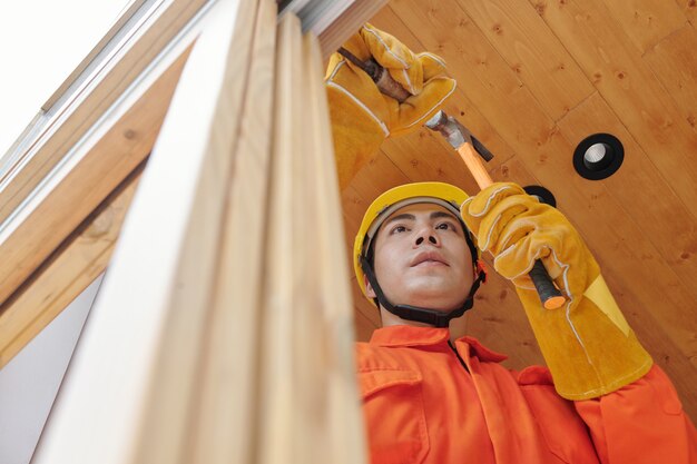 Appaltatore che rimuove i vecchi telai di finestre in legno in casa prima di installarne di nuovi