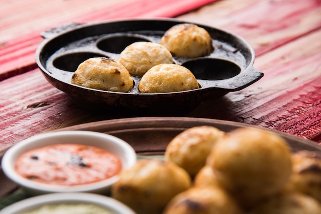 Appam o Mixed dal o Rava Appe serviti su uno sfondo lunatico con chutney verde e rosso. Una popolare ricetta per la colazione dell'India meridionale a forma di palla. Messa a fuoco selettiva