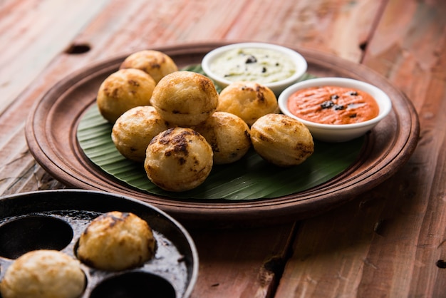 Appam o Mixed dal o Rava Appe serviti su uno sfondo lunatico con chutney verde e rosso. Una popolare ricetta per la colazione dell'India meridionale a forma di palla. Messa a fuoco selettiva