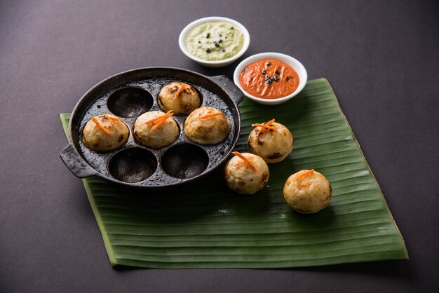 Appam o Mixed dal o Rava Appe serviti su uno sfondo lunatico con chutney verde e rosso. Una popolare ricetta per la colazione dell'India meridionale a forma di palla. Messa a fuoco selettiva