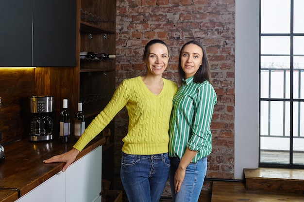 Appartamento loft per famiglia della classe media, sorelle graziose e snelle in posa in cucina.