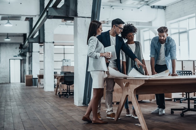 Appassionato del loro progetto. Gruppo di giovani imprenditori che lavorano insieme in un ufficio creativo