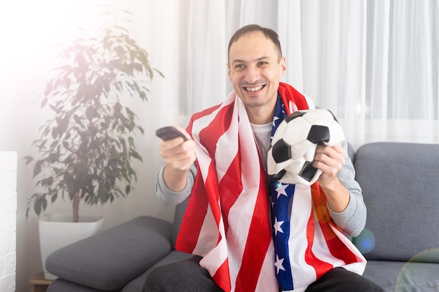 Appassionato di calcio. Ragazzo emotivo che grida celebrando la vittoria della squadra che tiene la palla in posa sullo sfondo dello studio. Foto di alta qualità