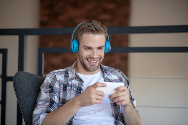 Appassionato di smartphone. Un uomo gioioso afferrato con il suo smartphone