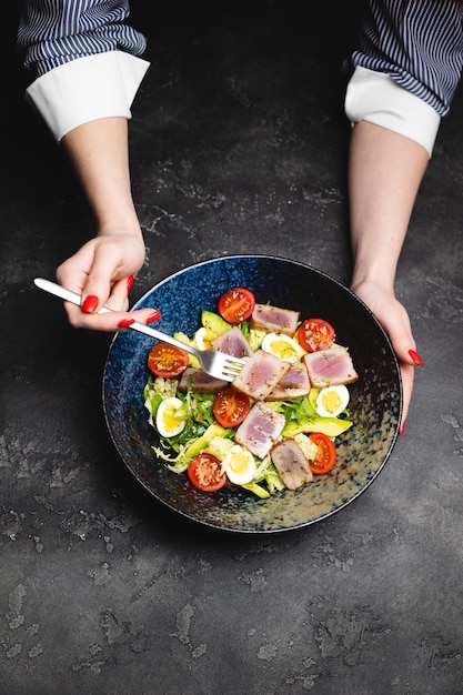 Appetitosa insalata nicoise in un bel piatto profondo su uno sfondo scuro