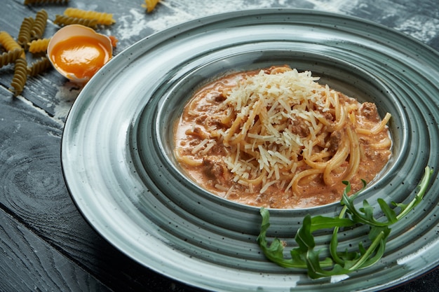 Appetitosa pasta fatta in casa alla bolognese con salsa rossa e carne macinata, parmigiano in un piatto blu. Primo piano, vista dall'alto. Spaghetti italiani, foto per la ricetta