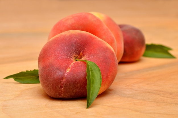 Appetitose pesche piatte fresche su fondo di legno da vicino