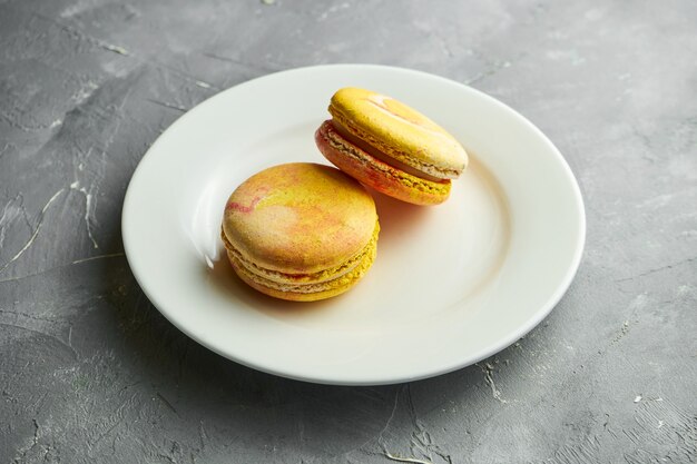 Appetitosi biscotti amaretti di farina di mandorle con intercalare di mango serviti in un piatto bianco su grigio