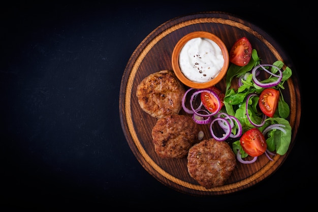 Appetitosi cotoletta di carne e insalata di pomodori con rucola