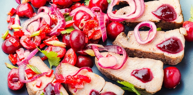 Appetitoso maiale al forno con frutti di bosco, salsa di ciliegie per carne.