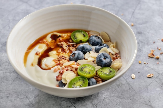 Appetitoso muesli fatto in casa con frutti di bosco e yogurt servito in una ciotola su sfondo scuro.