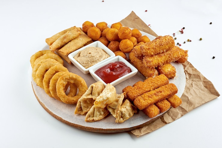 Foto appetitoso spuntino alla birra - un set di snack fritti, mozzarella, anelli di cipolla, bastoncini di pesce, crocchette di patate con salsa e su una tavola di legno. superficie bianca
