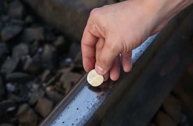 Appiattire le monete sui binari ferroviari all'aperto.