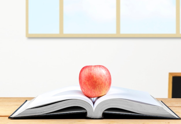 Apple al centro di un libro aperto sul tavolo di legno. Ritorno al concetto di scuola