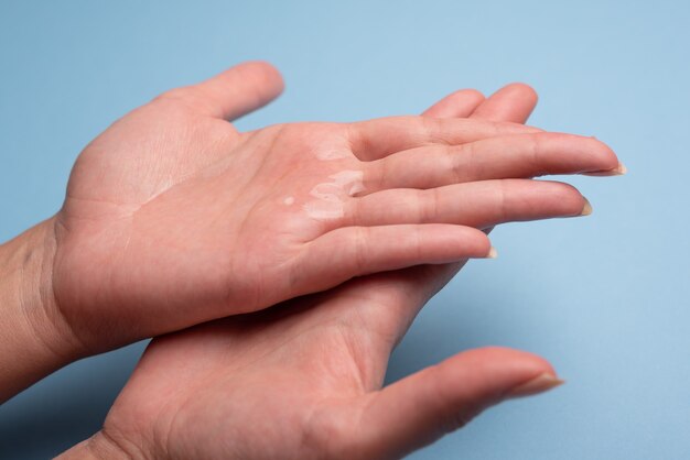 Applicazione di gel igienico nelle mani su un blu chiaro