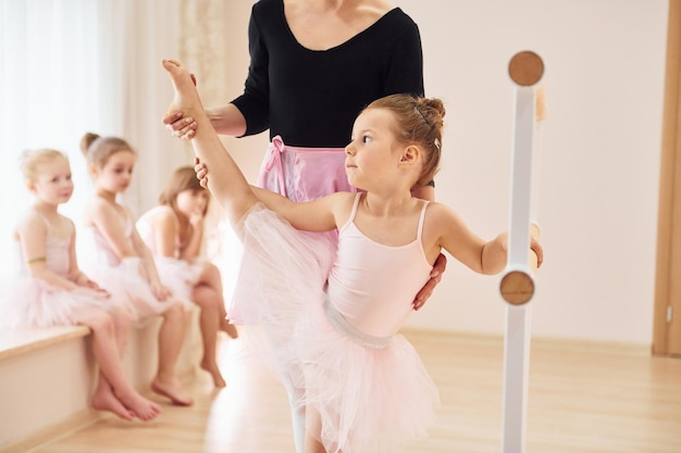 Appoggiata al piedistallo di legno Piccole ballerine si preparano per la performance