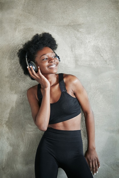 Appoggiato al muro. Ritratto di ragazza afro-americana in abiti fitness avendo una pausa dopo l'allenamento