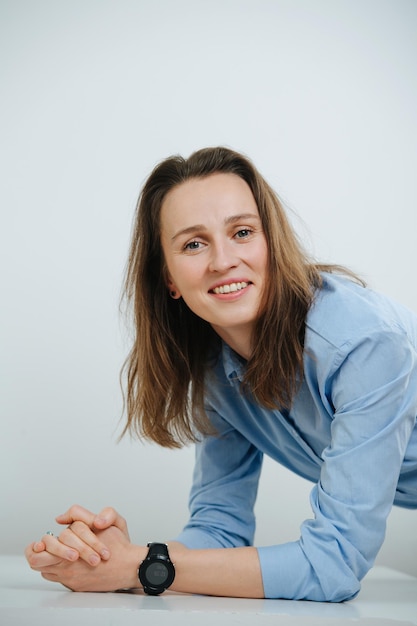 Appoggiato su un tavolo donna d'affari sorridente in camicia blu con i capelli lunghi