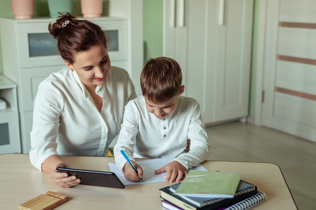 apprendimento a distanza, istruzione online a casa. famiglia mamma e figlio facendo i compiti con gioia nella stanza facendo uso della compressa