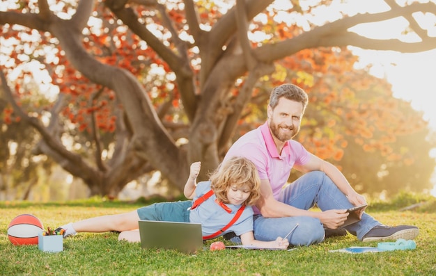 Apprendimento all'aperto padre e figlio che giocano o studiano con il laptop nel parco