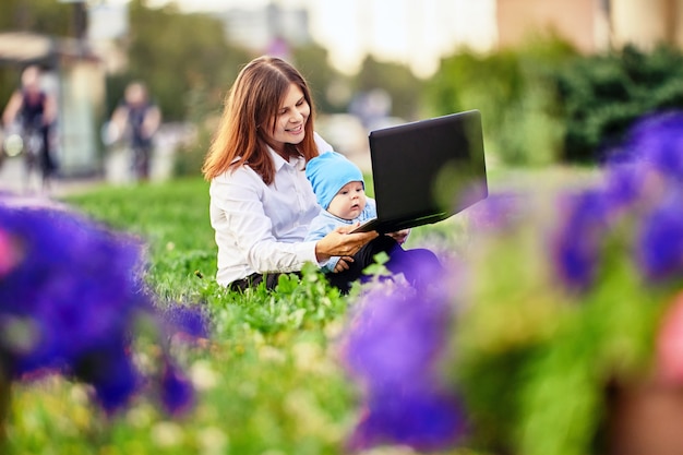 Apprendimento online da parte di una donna con un bambino che utilizza un laptop all'esterno