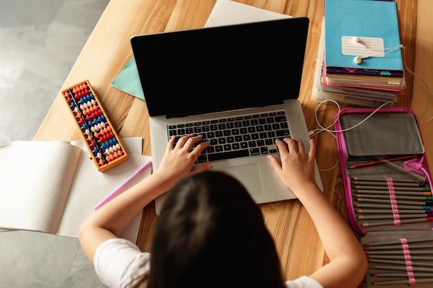 Apprendimento online. La ragazza con un computer portatile fa i compiti a casa. Studentessa studia con una videochiamata. Formazione a distanza durante la quarantena