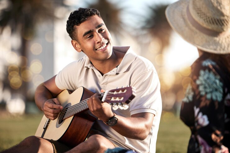 Foto appuntamento di picnic e uomo con chitarra per l'amore romanticismo e anniversario a porto rico coppia felice e musica in escursione sull'erba per l'estate rilassarsi o felicità insieme al tramonto con strumento nel parco
