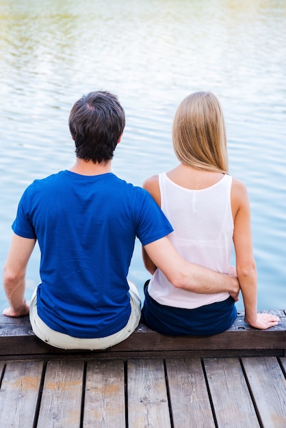 Appuntamento romantico. Vista posteriore di una giovane coppia di innamorati seduti insieme sulla banchina