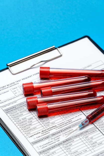 Appunti con modulo vuoto di carta con provette per analisi del sangue su sfondo blu.