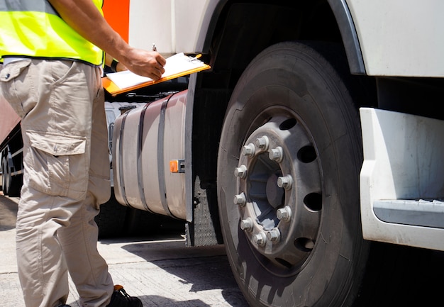 appunti della tenuta della mano dell'autista di camion con l'ispezione delle gomme di un camion.