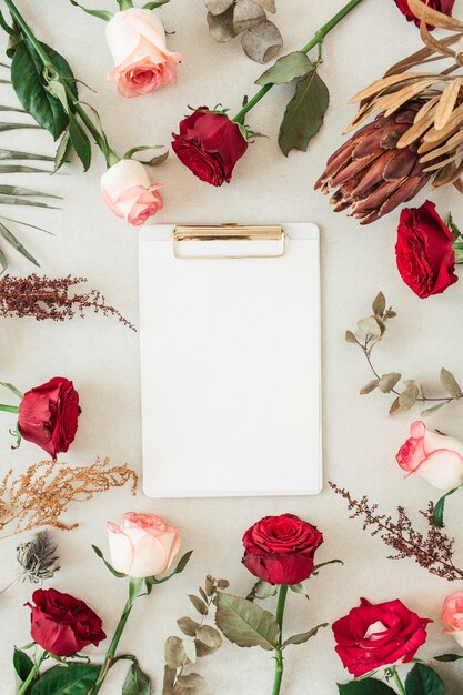 Appunti piatti laici con spazio vuoto della copia per il testo nel bordo della cornice di fiori rosa, rosa rossa, protea, foglia di palma tropicale, eucalipto su beige