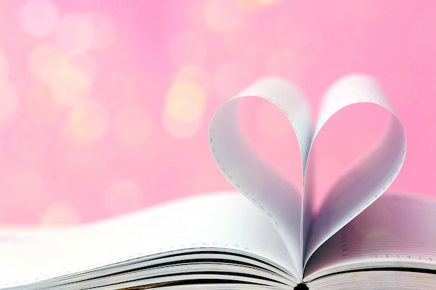 Apra il libro con forma del cuore sul fondo leggero di rosa del bokeh. Concetto di San Valentino. Stile minimal