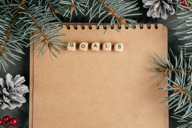 Apra il taccuino piegato di carta kraft marrone con obiettivi scritti su cubi di legno. Natale e Capodanno. Vista dall'alto. Copia spazio