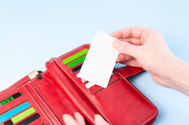 Apra la borsa rossa e le mani prendono una carta Carta di credito nel portafoglio Composizione semplice su sfondo blu Le mani prendono una carta da una borsa Paga soldi