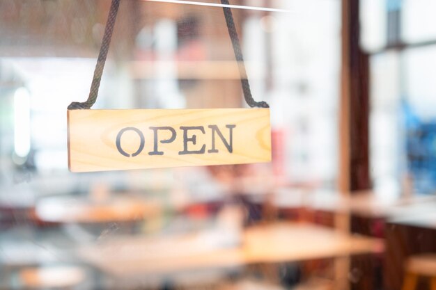 Aprire il cartello in legno ampio attraverso il vetro della finestra presso la caffetteria