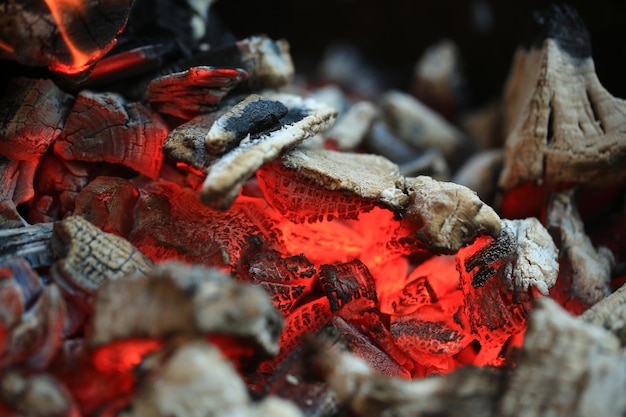 Aprire il fuoco con cenere calda e carbone che brucia con fiamma arancione brillante come sfondo astratto