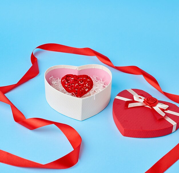 Aprire la confezione regalo rossa a forma di cuore con un fiocco sul blu