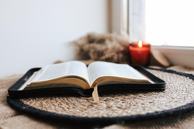 Aprire la Sacra Bibbia su un vecchio tavolo di legno e uno sfondo bianco della parete Concetto di religione Accogliente foto calda