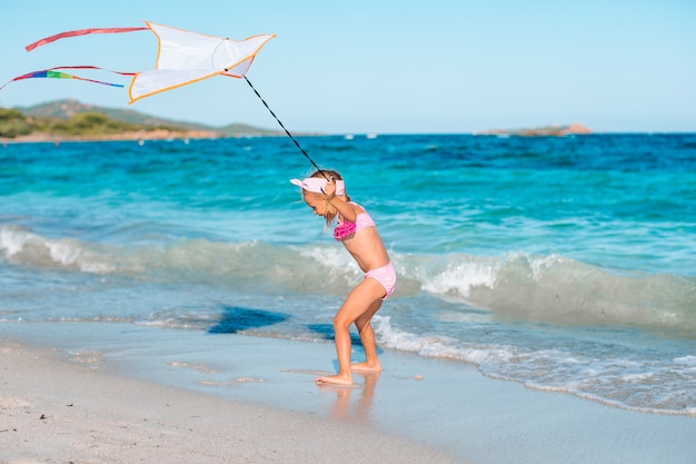 Aquilone di volo della bambina sulla spiaggia tropicale